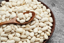 Raw White Beans And Spoon In Bowl On Grey Table, Top View