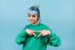 © bodnarphoto - Beautiful teen girl in a green sweatshirt and colored waltz shows a heart gesture and looks at the camera with a smile on his face.