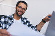 © BullRun - Portrait of skilled male employee in classic spectacles holding paper report and looking at camera during time for marketing analyzing in office, professional financial expert posing at desktop