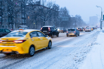 Canvas Print - cars drive on snowy city road in blue winter dusk