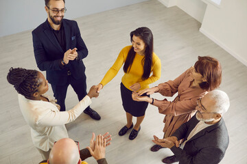 Top view of diverse businesswomen shake hands get acquainted greeting at team meeting. Multiethnic female colleagues or business partners shake hands congratulate with deal close or agreement.