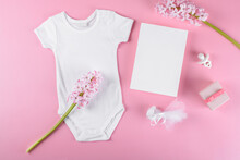 Baby Shower Invitation 5x7 Card Mockup With Baby Accessories Girl Bodysuit, Nipple Or Baby's Dummy, Gift Box And Confetti And Pink Hyacinth Flowers With Copy Space On Pink Pastel Color Background