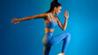 © Prostock-studio - Sporty Female Standing Doing Elbow To Knee Crunch, Blue Background