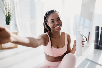 Canvas Print - Smiling young African American lady with bottle of water taking selfie on break from home workout