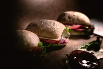 Wall Mural - Delicious ciabatta sandwiches with cheese, salami, tomatoes, cucumbers and lettuce. Fresh square sandwiches on the table