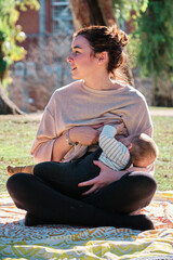 Young woman breastfeeding her son outdoors in a public park