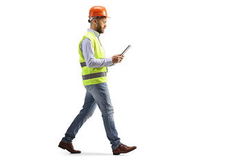 engineer with a hardhat walking and reading a document