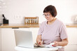 © Andriy Medvediuk - Concentrated senior woman in eyeglasses calculating utility bills or domestic expenditures,doing financial paperwork,paying for services, insurance using computer e-banking application alone at home.