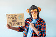 © karrastock - Man with monkey mask showing a sign that says SAVE THE PLANET.