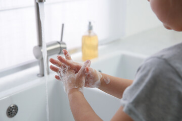 Wall Mural - Little girl washing hands with liquid soap at home, closeup