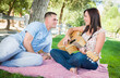 © Andy Dean - Young Adult Girl Playing Guitar with Boyfriend In The Park.