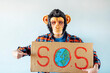 © karrastock - Man with monkey mask showing a sign that says S.O.S.