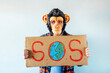 © karrastock - Man with monkey mask showing a sign that says S.O.S.