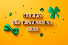 Top View Photo Of Wooden Cubes Labeled Happy St Patricks Day Shamrock Shaped Confetti And Green Bow-tie On Isolated Yellow Background