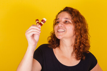 Caucasian, Brazilian, Latin American woman, curly hair, curls, yellow background, smiling, holding cheese and guava skewers, surprised face, romeo and juliet, sweet, delicious