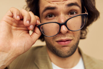 Attractive man with glasses emotions gesture hands posing beige background