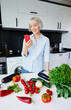 © luengo_ua - Helthy diet. Happy senior woman preparing vegetables on the kitchen using recipe on the smartphone.