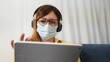 © maxximmm - telework. woman in a medical mask works remotely in a digital tablet wearing a medical protective mask. office home telework concept. woman in a medical protective mask works at freelance home