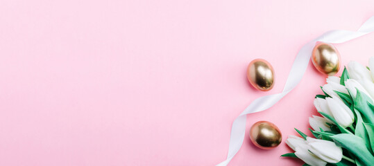 Wall Mural - Golden eggs with spring white tulips on pastel pink background in Happy Easter decoration. Foil minimalist egg design, modern top view banner design.