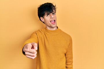 Poster - Handsome hipster young man wearing casual yellow sweater pointing displeased and frustrated to the camera, angry and furious with you