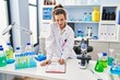 © Krakenimages.com - Young woman wearing scientist uniform listening to music writing report at laboratory