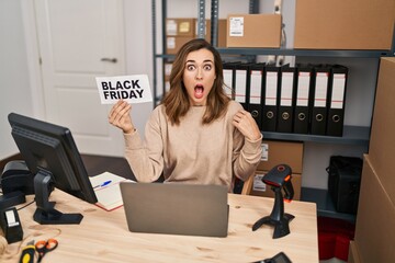 Poster - Young beautiful woman holding black friday banner small commerce scared and amazed with open mouth for surprise, disbelief face