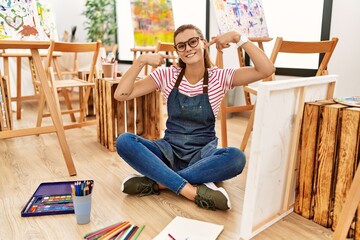 Sticker - Young brunette woman at art studio sitting on the floor smiling cheerful showing and pointing with fingers teeth and mouth. dental health concept.