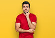 © Krakenimages.com - Hispanic man with beard wearing casual red t shirt looking confident at the camera with smile with crossed arms and hand raised on chin. thinking positive.