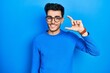 © Krakenimages.com - Young hispanic man wearing casual clothes and glasses smiling and confident gesturing with hand doing small size sign with fingers looking and the camera. measure concept.