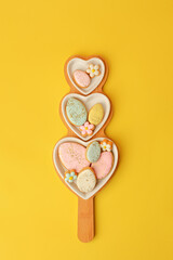 Wall Mural - Sweets, pastry, gingerbread cookies for Easter table. Easter eggs heart shaped decor  on yellow background top view copy space, spring seasonal holiday banner for your site, flyer, coupon