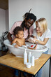 © Roman - excited black and caucasian parents washing daughter child girl in small bathtub, playing with soap and foam, at home, have fun together, laughing. clean skin, skincare, childhood, lifestyle concept