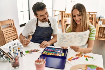 Two students smiling happy painting sitting on the table at art school.