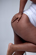 © Roman - Plus Size Model. Woman Hips Close Up. Unrecognizable Female In White Bodysuit, Posing On Gray Studio Background. Body Positive Concept. Black Chubby Plump Lady Is Sexy, Keeping Hands On Hips