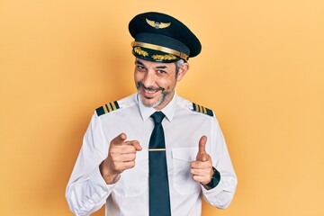 Poster - Handsome middle age man with grey hair wearing airplane pilot uniform pointing fingers to camera with happy and funny face. good energy and vibes.