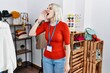 © Krakenimages.com - Young caucasian woman working as manager at retail boutique shouting and screaming loud to side with hand on mouth. communication concept.