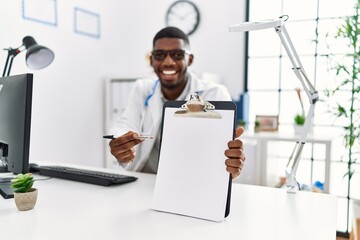 Wall Mural - Young african american man wearing doctor uniform working at clinic