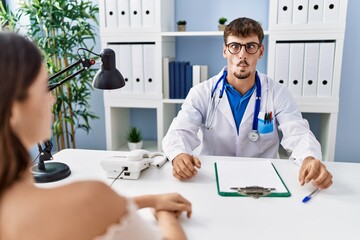 Canvas Print - Young doctor with client at medical clinic making fish face with lips, crazy and comical gesture. funny expression.