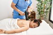 © Krakenimages.com - Middle age man and woman wearing therapist uniform having back massage session using percussion pistol at beauty center