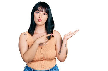 Poster - Young hispanic plus size woman pointing open palm with finger looking at the camera blowing a kiss being lovely and sexy. love expression.