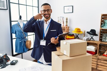 Poster - African american man working as manager at retail boutique pointing with hand finger to face and nose, smiling cheerful. beauty concept