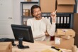 © Krakenimages.com - Handsome middle age man working at small business ecommerce with a big smile on face, pointing with hand and finger to the side looking at the camera.