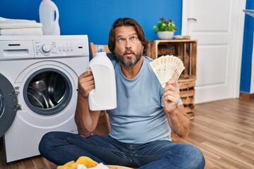 Poster - Handsome middle age man saving money of laundry detergent making fish face with mouth and squinting eyes, crazy and comical.