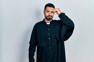 Sticker - Handsome hispanic man with beard wearing catholic priest robe worried and stressed about a problem with hand on forehead, nervous and anxious for crisis