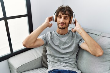 Sticker - Young hispanic man smiling confident listening to music at home