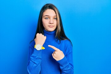 Poster - Young brunette girl wearing turtleneck sweater in hurry pointing to watch time, impatience, looking at the camera with relaxed expression