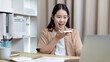 © Puwasit Inyavileart - Asian woman talking on the phone and working on a laptop with a smiling face, Business Cell Phone Conversations, Working at home, Home lifestyle, Stay home, New normal, learning, Social distancing.