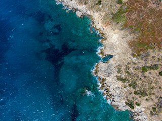 Aerial drone view of sea and rocks on the beach. Beautiful natural rocky beach at summer. Waves crushing on wild beach at sunset. Coastline. Transparent sea water.	