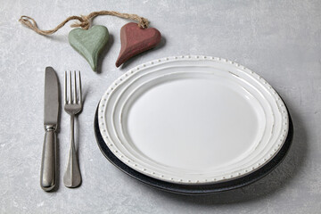 Wall Mural - An empty white plate with cutlery and two decorative wooden hearts