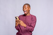 © wazkkii - Happy black guy with mobile phone looking at smart phone with mouth wide open copy space, white background, panorama