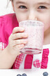 Young girl drinking from a glass of yoghurt with blueberry fruits